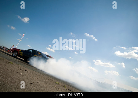 Muscle-Car Autos tun einen Burnout an einen Dragstrip, drehen die Räder Reifen Ausbrennen smokey Rauch Kautschuk glatt Slicks Heizung dr Stockfoto