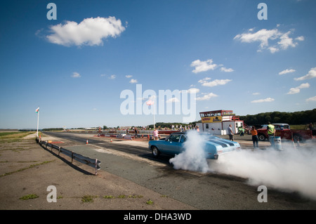 Muscle-Car Autos tun einen Burnout an einen Dragstrip, drehen die Räder Reifen Ausbrennen smokey Rauch Kautschuk glatt Slicks Heizung dr Stockfoto