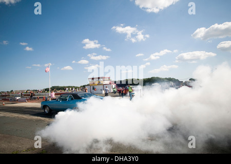 Muscle-Car Autos tun einen Burnout an einen Dragstrip, drehen die Räder Reifen Ausbrennen smokey Rauch Kautschuk glatt Slicks Heizung dr Stockfoto