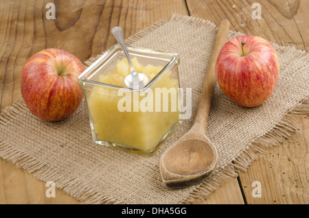 Apfelkompott und Löffel in ein Glas auf einem Holztisch Stockfoto