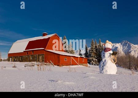 Schneemann verkleidet als Cowboy steht man vor einem Vintage rote Scheune im Winter; Palmer Alaska Usa Stockfoto