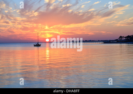 Die Silhouette eines Segelbootes vertäut in der englischen Marine Cove aus Gulf Breeze, Florida bei Sonnenuntergang Stockfoto
