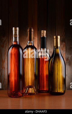 Vier Flaschen Wein, Holz im Hintergrund. Die Flaschen haben kein Label und die Textur der Hintergrund durchscheint. Stockfoto