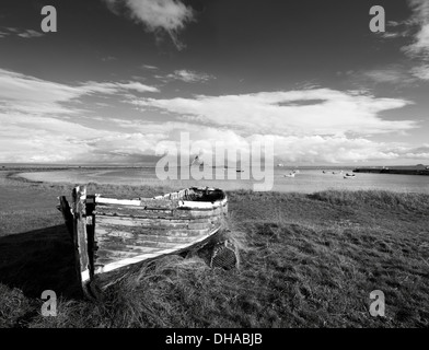 Alte hölzerne entgeisterung Fischerboote auf Holy Island und die fernen Lindisfarne Burg in Monochrom, Northumberland, England, UK Stockfoto