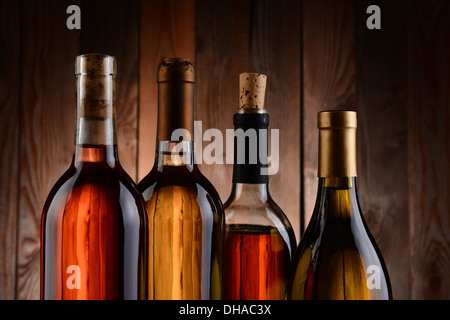 Vier Flaschen Wein, Holz im Hintergrund. Die Flaschen haben kein Label und die Textur der Hintergrund durchscheint. Stockfoto