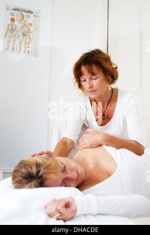 Durchführung einer Shiatsu-Massage in einem weißen Behandlungsraum masseur Stockfoto