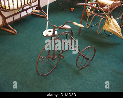 Dieses alte Kinderdreirad ist ein klassisches Beispiel für Kinderspielzeug aus dem frühen 20. Jahrhundert. Es verfügt über ein einfaches Design, typischerweise mit großen Vorderrädern und einem kleinen Hinterrad und ist Teil der Geschichte der Kinderspielsachen. Stockfoto