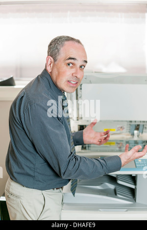 Business-Mann Probleme mit Kopierer im Büro suchen, frustriert und wütend Stockfoto