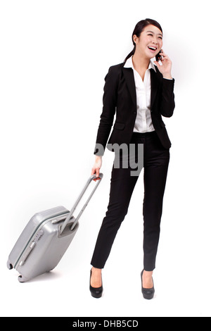 Geschäftsfrau mit einem Handy ziehen einen Koffer Stockfoto