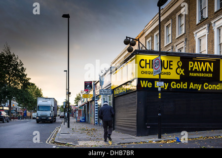 Ein Mann geht vorbei an einem Pfandleiher auf dem Caledonian Road in Islington, Nordlondon, an einem Sonntagmorgen im November. Stockfoto