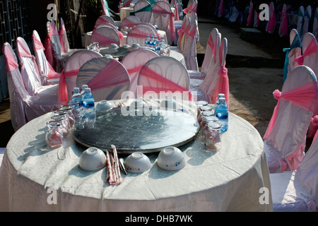 Tabellen sind formell und Stühle sind in rosa Bändern für ein bevorstehendes Ereignis auf einer Stadtstraße in Kampong Cham, Kambodscha drapiert. Stockfoto