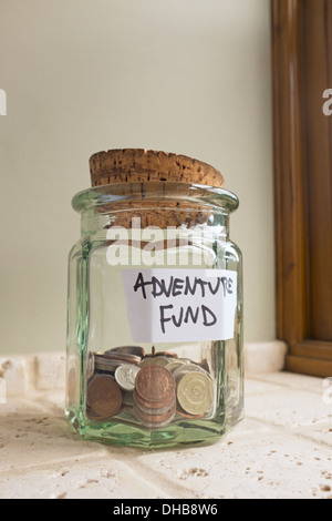 Glas mit der Aufschrift Abenteuer Fonds mit Kleingeld. Stockfoto