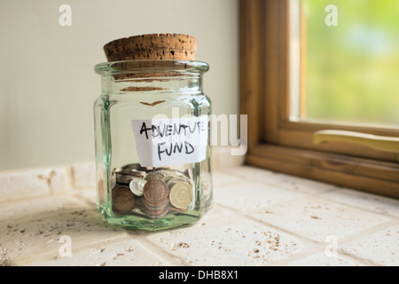 Glas mit der Aufschrift Abenteuer Fonds mit Kleingeld. Stockfoto