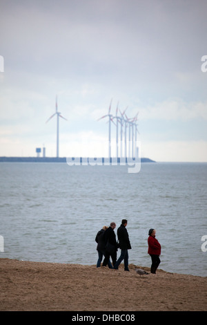 Menschen am Strand von Knokke, Flandern, Belgien, mit der Windkraftanlagen Park Windparks in Zeebrugge hinter. Stockfoto