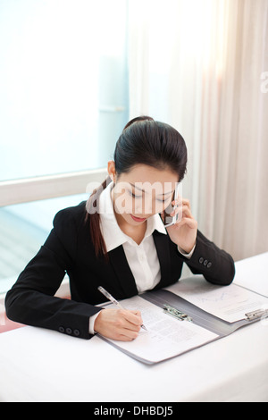 Geschäftsfrau, reden am Telefon beim Signieren von Dokumenten Stockfoto