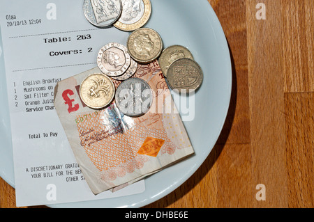 Geld als Zahlungsmittel mit der Rechnung auf eine Untertasse in einem Restaurant oder Café. Stockfoto