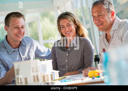 Eine Landhausküche. Ein Modell eines Hauses auf dem Tisch. Planung und Gestaltung ein Haus zu bauen. Drei Personen. Stockfoto