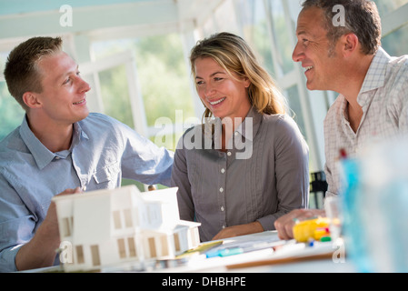Eine Landhausküche. Ein Modell eines Hauses auf dem Tisch. Planung und Gestaltung ein Haus zu bauen. Drei Personen. Stockfoto