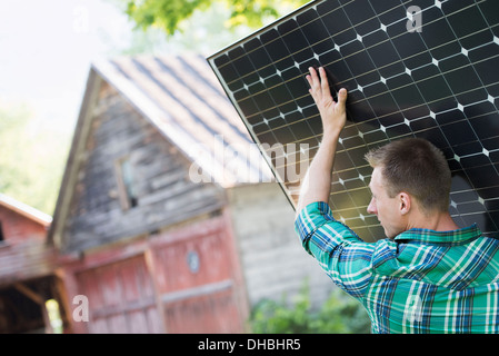 Ein Mann mit einem Solar-Panel für ein Gebäude im Bau. Stockfoto