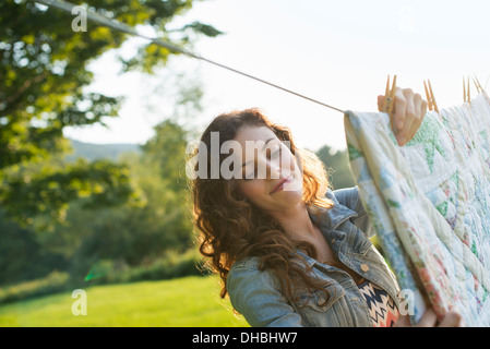 Eine Frau, das Aufhängen von Wäsche auf der Wäscheleine, an der frischen Luft. Stockfoto