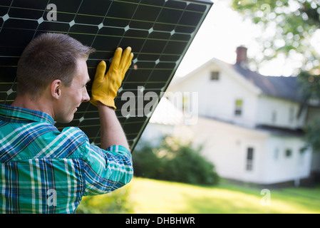 Ein Mann mit einem Solar-Panel für ein Gebäude im Bau. Stockfoto