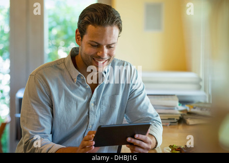 Eine Person allein in einem Café sitzen. Ein Mann mit einem digitalen Tablet. Stockfoto