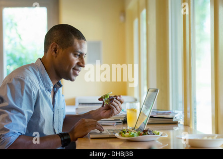 Eine Person allein in einem Café sitzen. Ein Mann auf einem Laptop arbeiten. Stockfoto