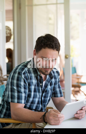 Ein Mann an einem Tisch mit einem digitalen Tablet. Stockfoto
