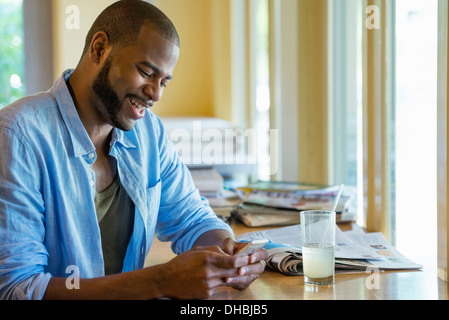 Ein Mann sitzt allein in einem Café, mit seinem Smartphone. Stockfoto