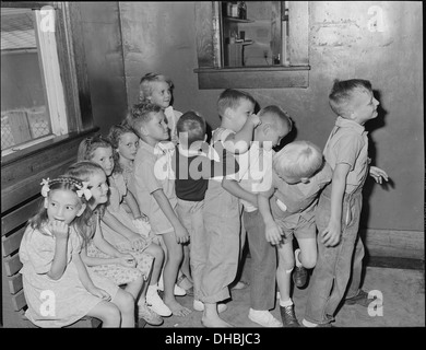 Kinder warten im Außenraum einer Arztpraxis auf Pockenimpfung und Vorschuluntersuchung. Das Bild spiegelt einen Moment in der frühen öffentlichen Gesundheit und medizinischen Versorgung von Kindern in der Mitte des 20. Jahrhunderts wider. Stockfoto