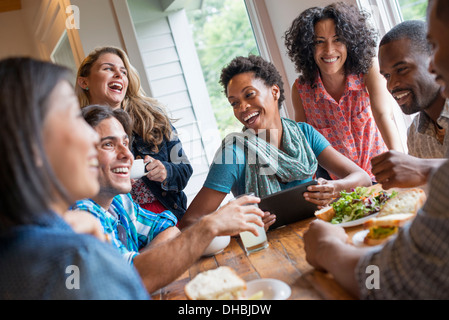 Eine Gruppe von Menschen treffen in einem Café für eine Mahlzeit. Verwenden digitale Tablets und Smartphones. Stockfoto