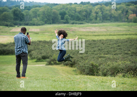 Ein Mann, ein Foto einer Frau springt in die Luft springen vor Freude mit ihren ausgestreckten Armen. Stockfoto