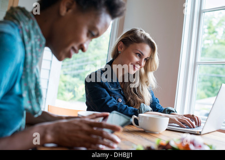 Zwei Frauen in einem Café. Verwenden digitale Tablet und Notebook. Arbeiten und in Kontakt zu bleiben. Stockfoto