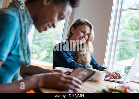 Zwei Frauen in einem Café. Verwenden digitale Tablet und Notebook. Arbeiten und in Kontakt zu bleiben. Stockfoto