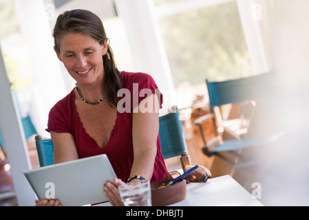 Eine Frau sitzt an einem Tisch mit einem digitalen Tablet. Stockfoto