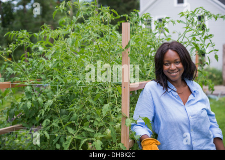 Eine Frau bei der Gartenarbeit. Stützte sich auf einen Zaun Lächeln auf den Lippen. Stockfoto