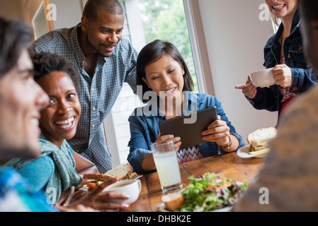 Eine Gruppe von Menschen treffen in einem Café für eine Mahlzeit. Verwenden digitale Tablets und Smartphones. Stockfoto