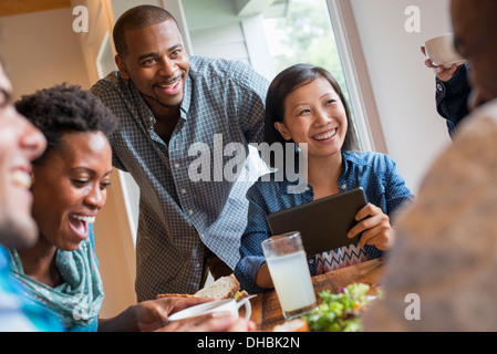 Eine Gruppe von Menschen treffen in einem Café für eine Mahlzeit. Verwenden digitale Tablets und Smartphones. Stockfoto