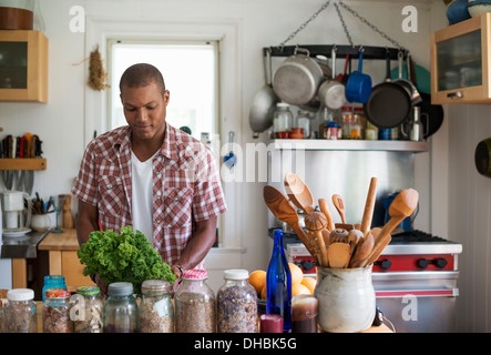 Ein junger Mann in der Küche vorbereiten, Salatblätter und Gemüse. Stockfoto