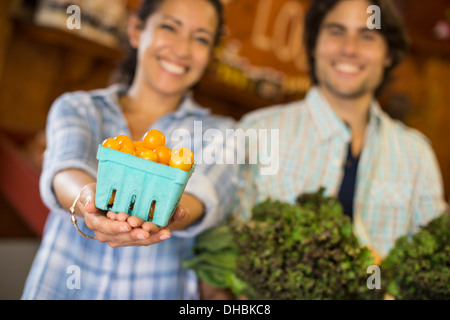 Zwei Personen mit Körben von Tomaten und geschweiften grünes Blattgemüse. Arbeiten auf einem Bio-Bauernhof. Stockfoto