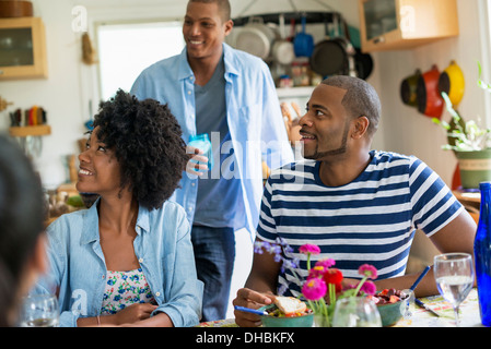 Eine Gruppe von Frauen und Männern bei einer Mahlzeit in einer Landhausküche. Stockfoto