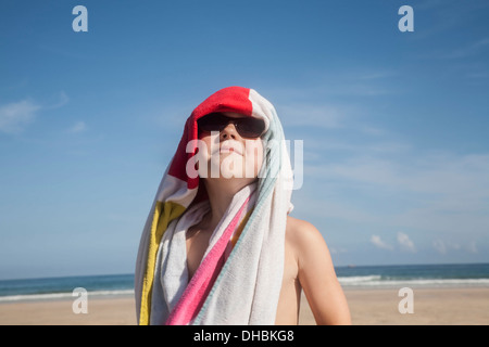 Ein Junge in Sonnenbrille mit einem Handtuch über dem Kopf. Stockfoto