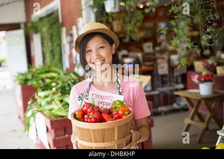 Eine Frau auf einem Bio-Bauernhof Stand, Anzeigen von frischem Gemüse zu verkaufen. Stockfoto