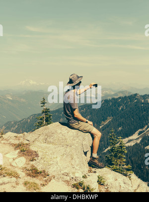 Ein Wanderer auf Berggipfel und halten Smartphone am besten Überraschung Mountain in alpinen Seen Wildnis in Mount Baker-Snoqualmie Stockfoto