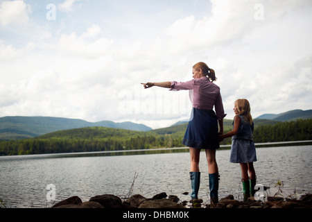 Zwei Menschen, eine Frau und ein Kind stehend nebeneinander und auf der Suche über Wasser. Stockfoto