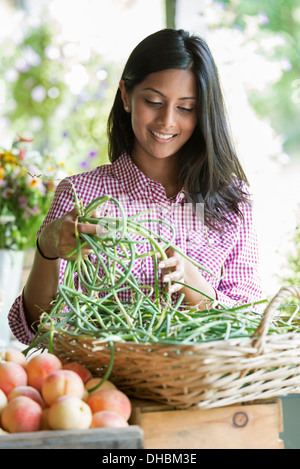 Ein Bauernhof Stand mit frischem Bio-Gemüse und Obst.  Eine Frau mit Trauben von Karotten. Stockfoto