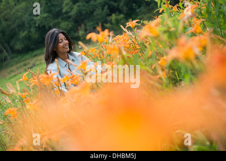 Eine Frau stand unter blühende Pflanzen auf einem Bauernhof. Stockfoto