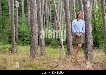 Eine Frau stand unter den Bäumen am Ufer eines Sees im Staat New York. Stockfoto