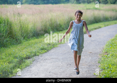 Ein junges Mädchen in einem Sommerkleid, zu Fuß entlang eines Pfades. Stockfoto