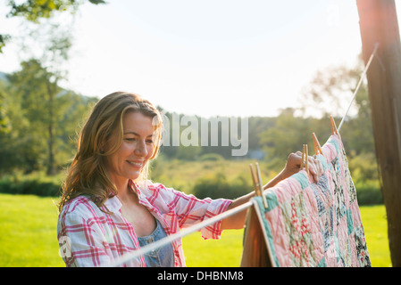 Eine Frau, das Aufhängen von Wäsche auf der Wäscheleine, an der frischen Luft. Stockfoto